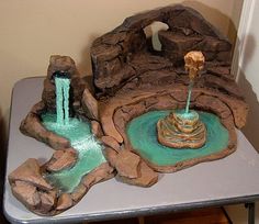 a table with a fountain and rocks on it in the shape of a rock house