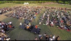 an aerial view of a large group of people in a field with one person on a stage