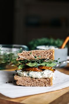 a sandwich is sitting on top of a cutting board next to a bowl of greens