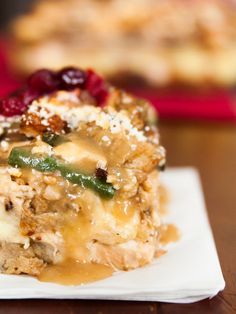 a piece of casserole on a white plate with cranberries and other toppings