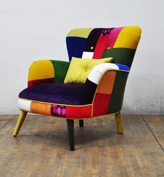 a multicolored chair sitting on top of a wooden floor next to a white wall