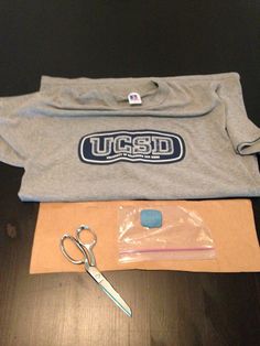 a pair of scissors, t - shirt and other items are laid out on a table