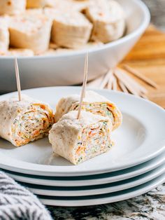 two white plates topped with food and toothpicks in them next to another plate