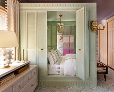 a bedroom with green walls and white shutters, an open door leading to a bed