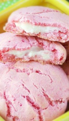 some pink cookies with white frosting are on a yellow plate