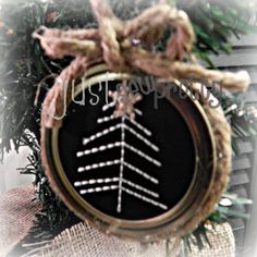 a christmas ornament hanging from a tree branch with needles in the shape of a snowflake