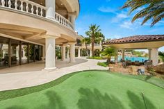 a large house with a golf course in front of it and palm trees on the other side