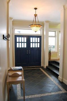 an entryway with two doors and steps leading up to the front door is lit by a chandelier