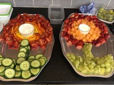 two trays filled with different types of fruits and vegetables on top of a counter