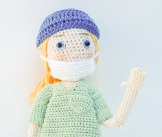 a crocheted doll wearing a face mask and holding a toothbrush in one hand