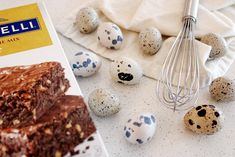 chocolate cake with speckled eggs next to it on a white tablecloth and in front of an egg carton