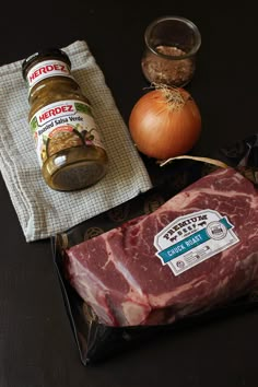 raw meat, spices and seasonings are on the table next to an onion jar