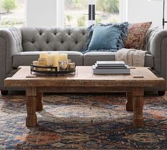 a living room with couches, coffee table and rug on the floor in front of large windows