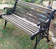 an empty park bench sitting in the grass