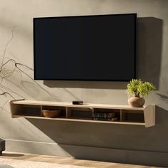 a tv mounted on the side of a wall next to a vase with flowers in it