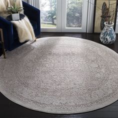 a living room area with a blue chair and white rug on the floor next to a window