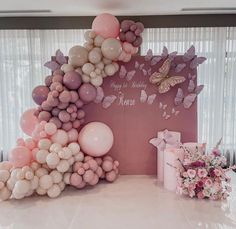 there is a large balloon arch with balloons and flowers on the wall next to it