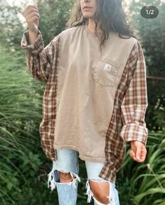 a woman wearing ripped jeans and a plaid shirt is standing in front of some bushes