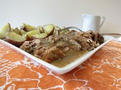 a white plate topped with meat covered in gravy and potatoes