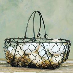 a wire basket filled with eggs sitting on top of a wooden table