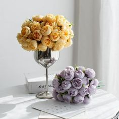 a vase filled with yellow and purple flowers on top of a table next to a book