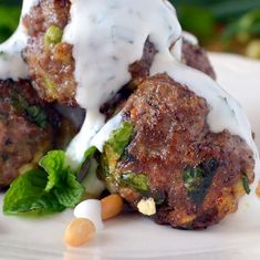 two meatballs covered in white sauce and garnished with green leafy vegetables