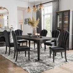 a dining room table with black chairs and a rug on the floor in front of it