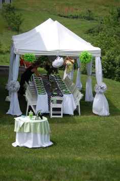 a white tent set up with chairs and tables for an outdoor wedding reception in the grass