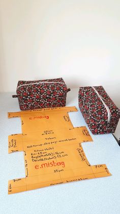 three pieces of luggage sitting on top of a white table next to an orange piece of paper