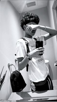 a young man taking a selfie in the mirror with his cell phone and camera