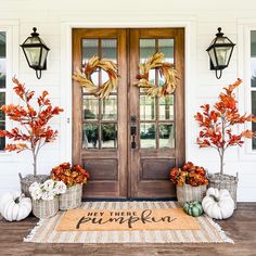 front door decorated for fall with pumpkins and gourds on the mat in front