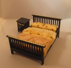 a dollhouse bed and night stand with yellow bedspread on the bottom half