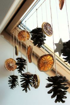 some pine cones hanging from a window sill next to a star and tree branch