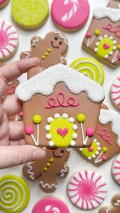 a hand is holding a decorated gingerbread house