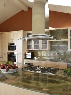 a bowl of fruit sitting on top of a kitchen counter next to an oven and stove