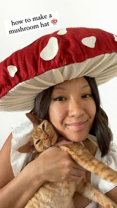 a woman holding a cat in her arms while wearing a mushroom hat