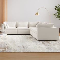 a living room with a large white sectional couch and coffee table on the rug in front of it