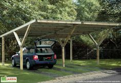 a car is parked under an attached carport in the grass with its trunk open