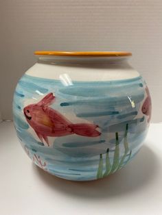 a ceramic fish bowl sitting on top of a white table next to a yellow pencil