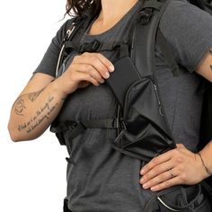 a woman wearing a black backpack with tattoos on her arm