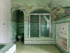 a bathroom with green and white tiles on the walls, flooring and shower stall