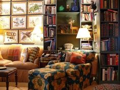 a living room filled with lots of furniture and bookshelves covered in pictures on the wall