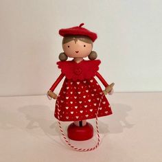 a doll is standing on top of a red base with white hearts in it's dress