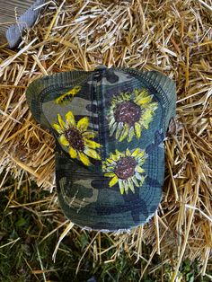 Add a splash of nature's beauty to your wardrobe with our hand-painted sunflowers and honey bee design on a camouflage distressed trucker's cap. Each cap is a unique work of art, individually painted with acrylic paint and care. Featuring three vibrant sunflowers against a camo backdrop, this hat is perfect for those who appreciate both style and the great outdoors. Stand out from the crowd with this one-of-a-kind accessory that blends rustic charm with floral elegance. For best care, hand wash Camo Backdrop, Honey Bee Design, Painted Sunflowers, Bee Design, Personalized Clothes, Personalized Christmas Ornaments, Great Outdoors, Honey Bee, Nature Beauty