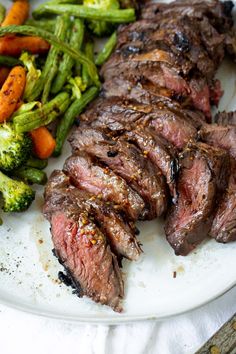 steak, broccoli and carrots are on a white plate with a fork