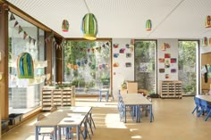 an empty classroom with tables and chairs in front of large windows