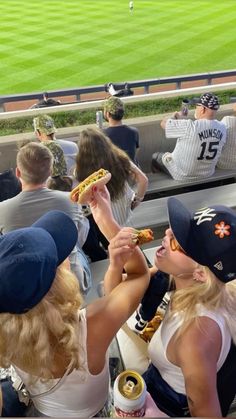 some people are eating hot dogs at a baseball game