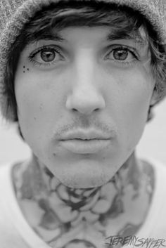 black and white photograph of a man with tattoos on his neck wearing a beanie