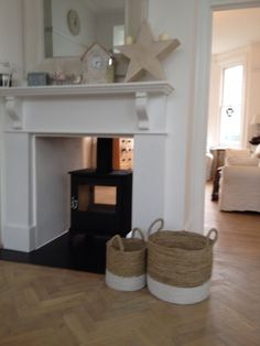 two baskets sitting on the floor in front of a fireplace