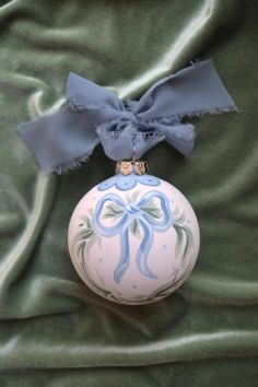 an ornament with a blue bow on it sitting on a green cloth covered bed